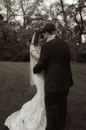 Black and white photo of bride and groom embracing outdoors on wedding day.