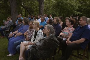 Wedding guests seated in rows of chairs outdoors at an intimate garden ceremony.