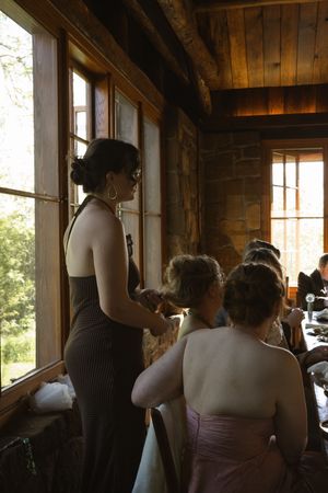 Wedding guests gather by rustic wooden windows inside a log cabin venue before the ceremony.