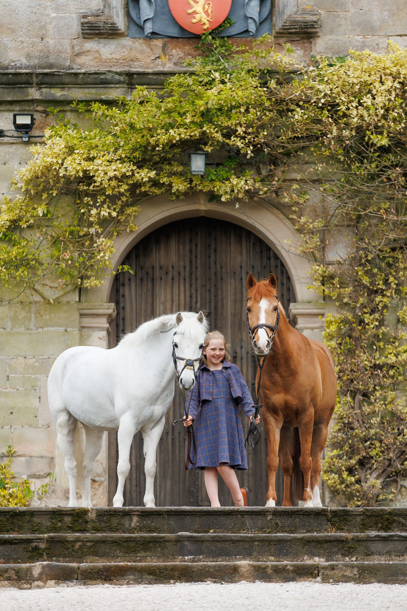 A brown horse and rider in a white sweater pose together against autumn foliage in soft natural lighting.