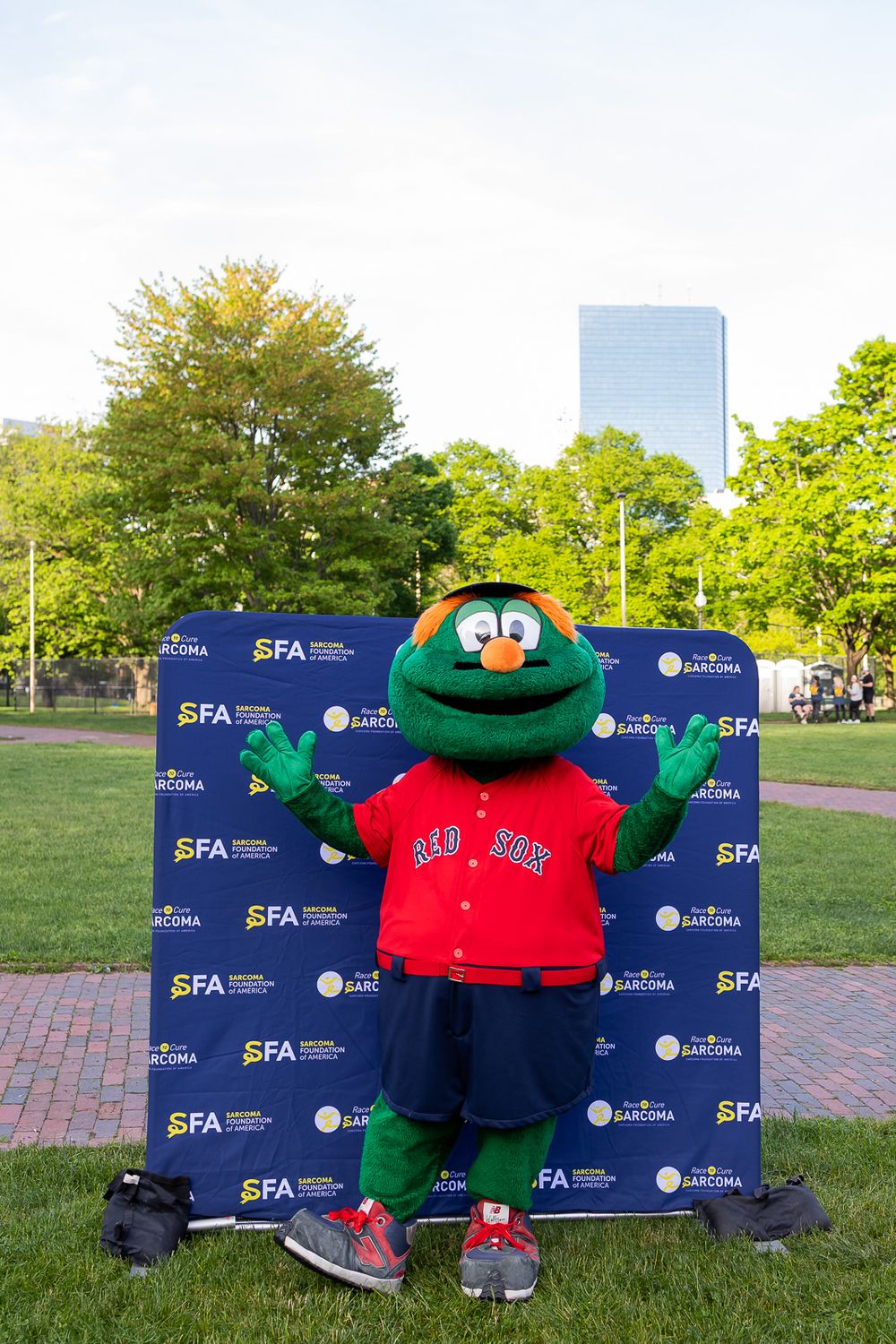 Wally the Green Monster Boston Red Sox mascot posing at an SFA Sarcoma Foundation event outdoors.