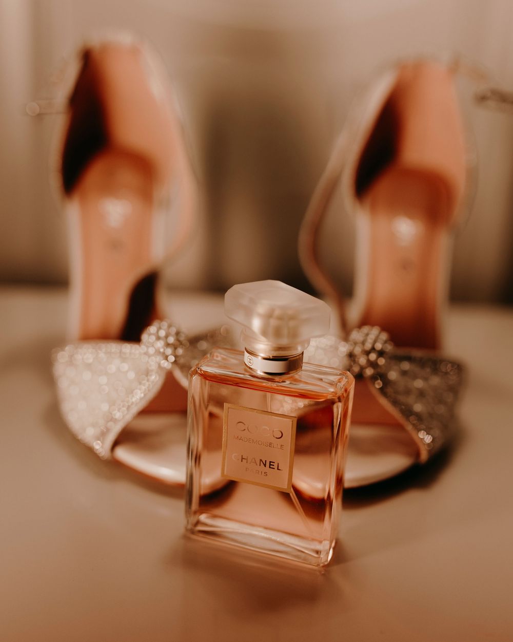 Chanel Coco Mademoiselle perfume bottle in focus with sparkling bridal heels in the background.
