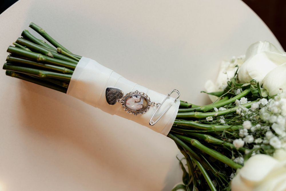 Bridal bouquet of white roses with vintage photo charm memorial keepsake wrapped in ribbon.