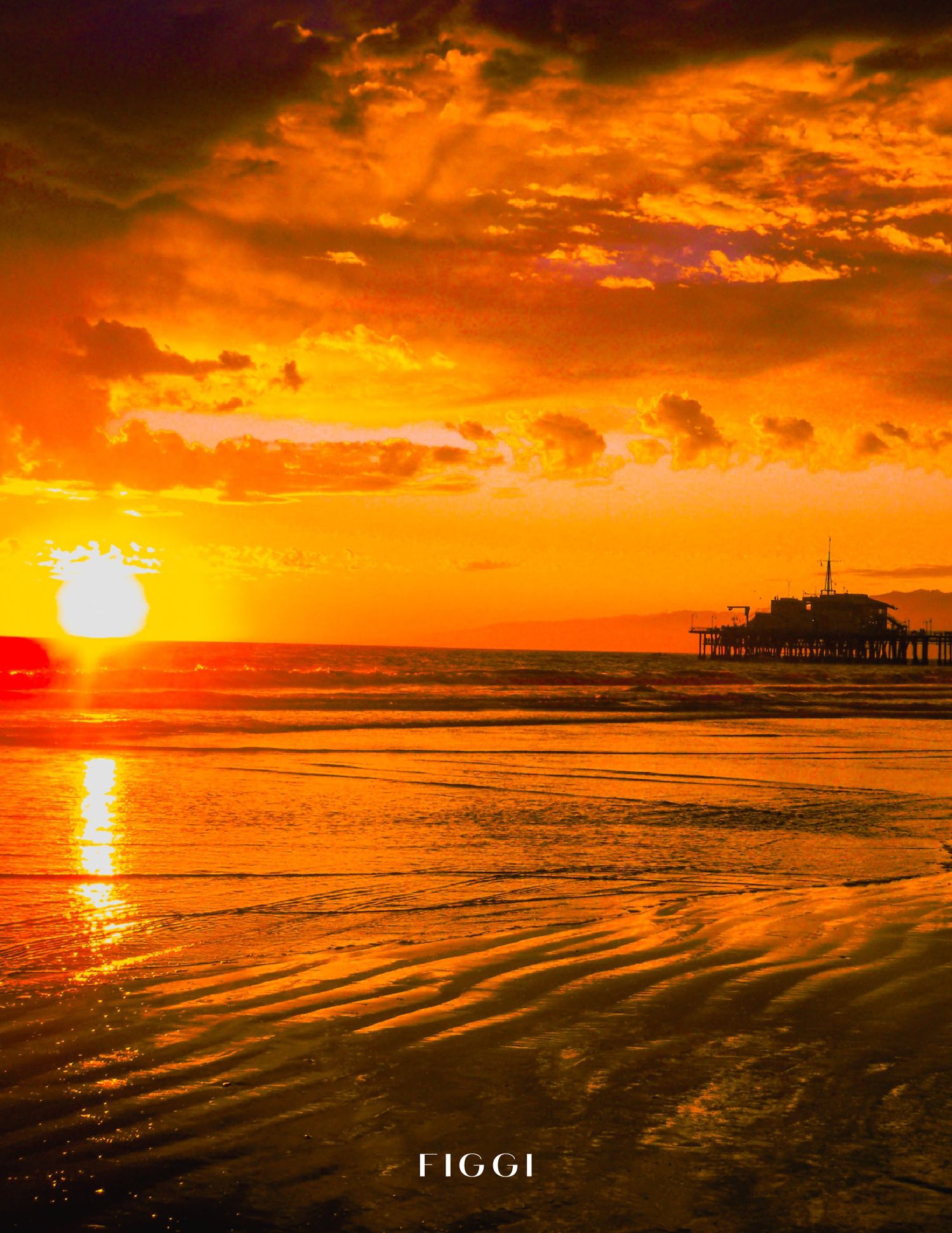 Golden sunset over ocean with pier silhouette, vibrant orange sky reflecting on wet sand at beach.