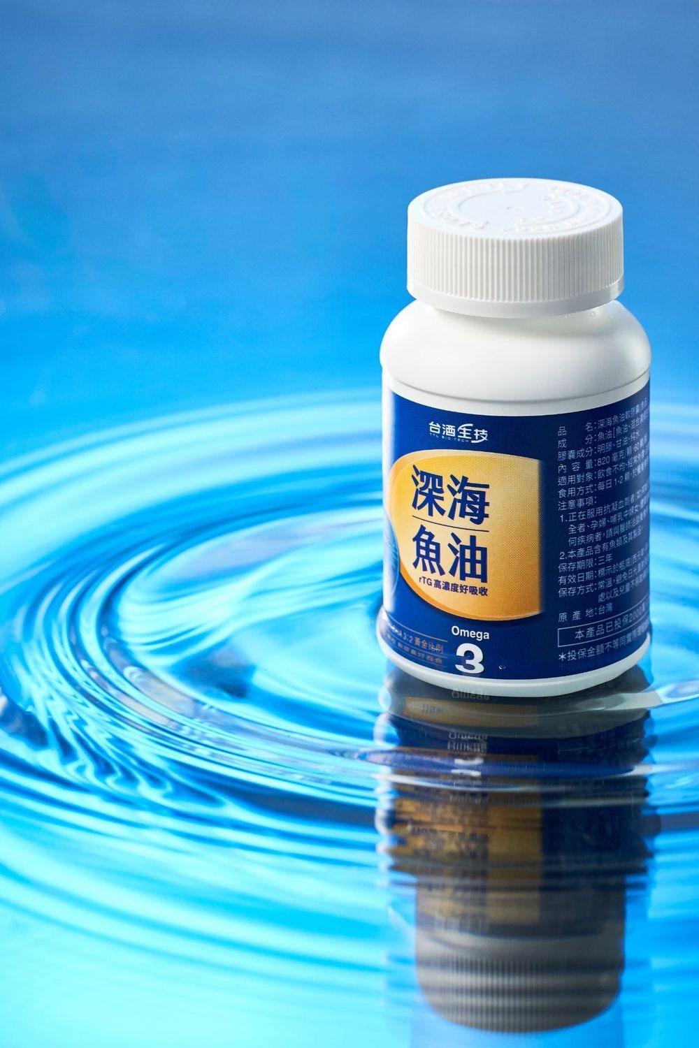 White bottle of deep sea fish oil Omega-3 supplements standing in blue rippling water, Chinese label.