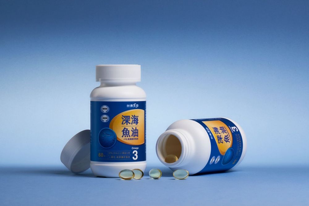 Deep sea fish oil omega-3 supplement bottles on blue background, one standing upright and one tipped over with capsules.