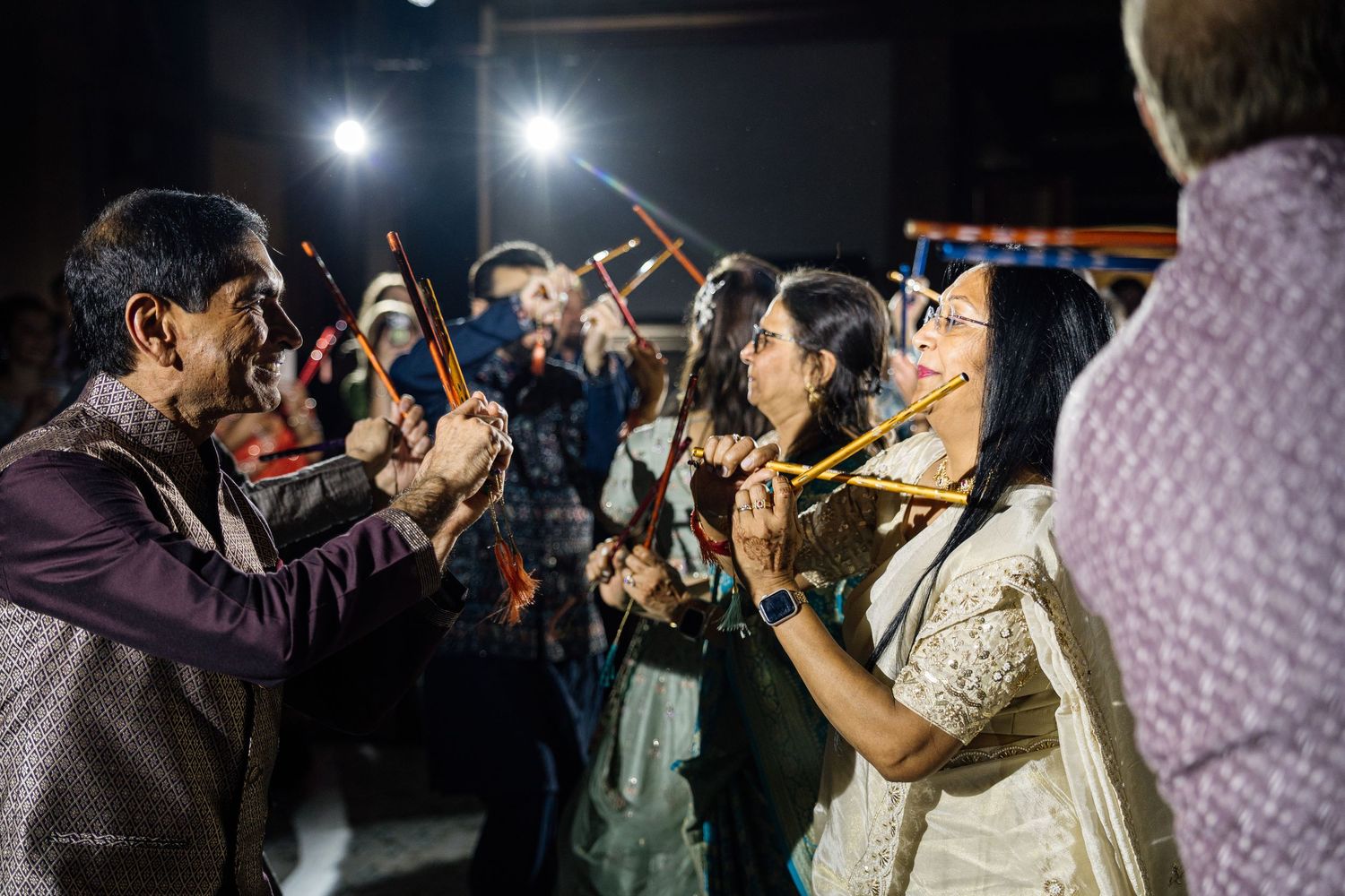 People playing dandiya sticks at a vibrant Indian Navratri celebration with festive lighting.