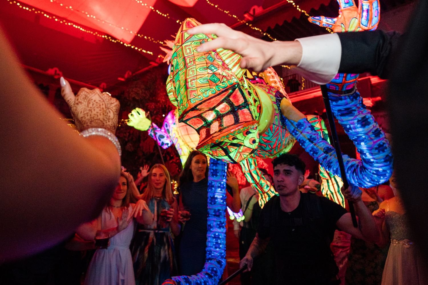 Colorful piñata being held at a vibrant party with festive lighting and excited guests.
