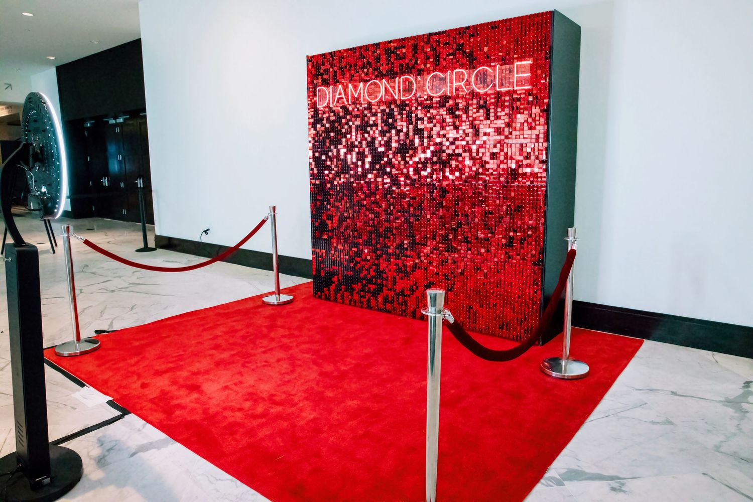 Red carpet entrance with Diamond Circle branded sequin backdrop and velvet rope stanchions.