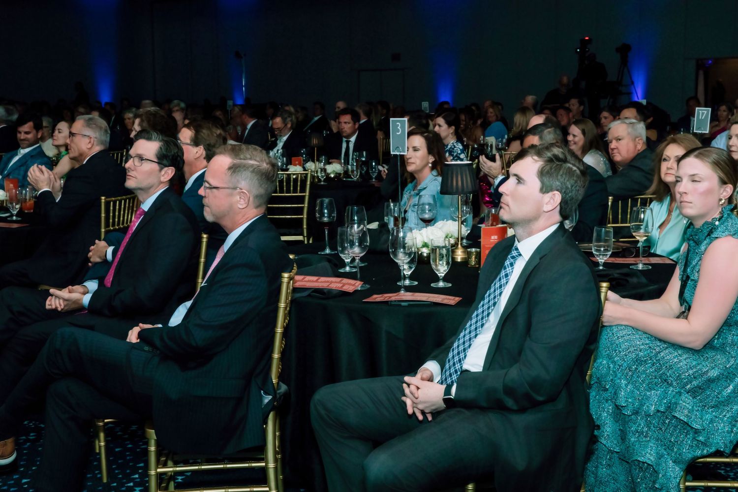 Guests in formal attire seated at tables during an elegant corporate gala or awards ceremony event.