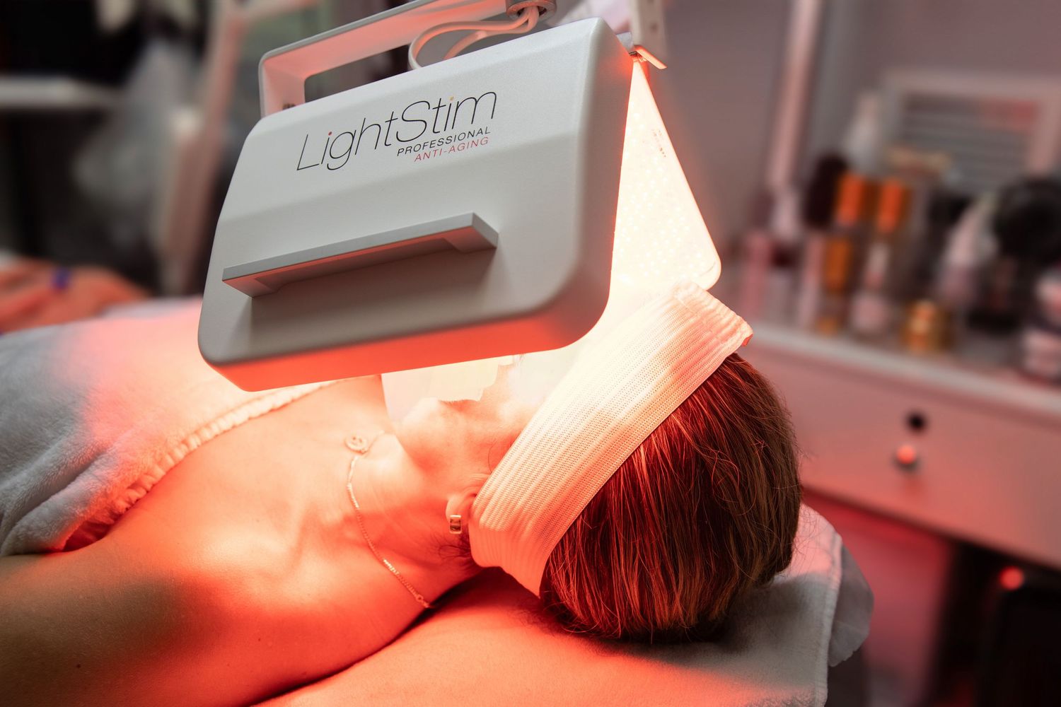 Person receiving LightStim LED light therapy facial treatment in a beauty salon setting.