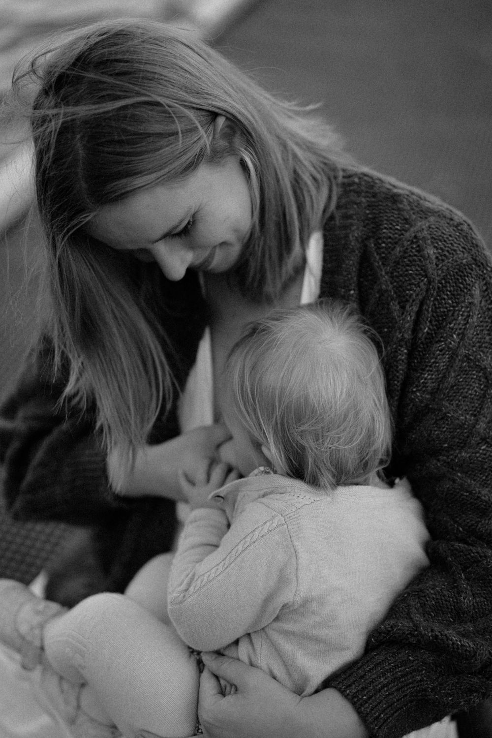 Black and white photo of a smiling mother tenderly holding her baby in her arms.