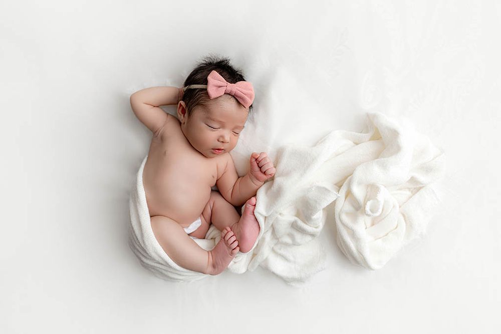 Mini newborn photos in Temecula California - baby girl sleeping peacefully wrapped in white swaddle.