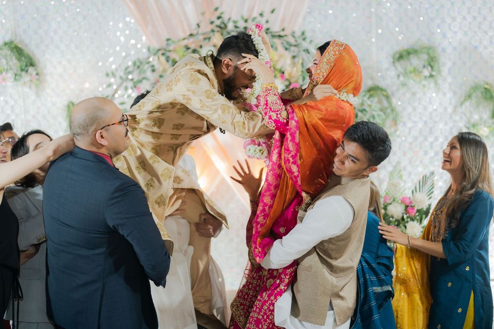 Guests lifting bride and groom during vibrant Indian wedding ceremony with colorful traditional attire.