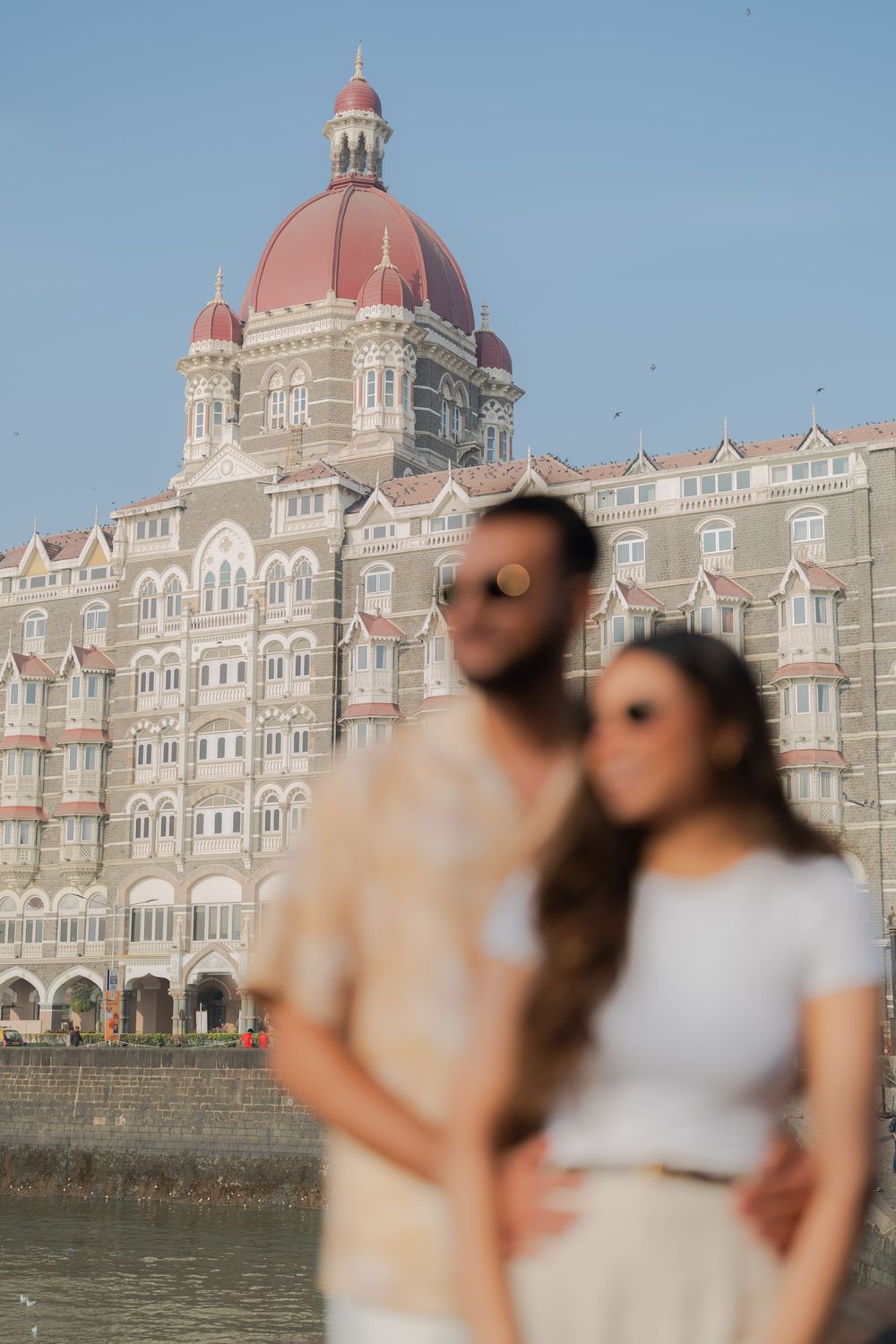 Couple posing in front of the iconic Taj Mahal Palace Hotel in Mumbai, India.