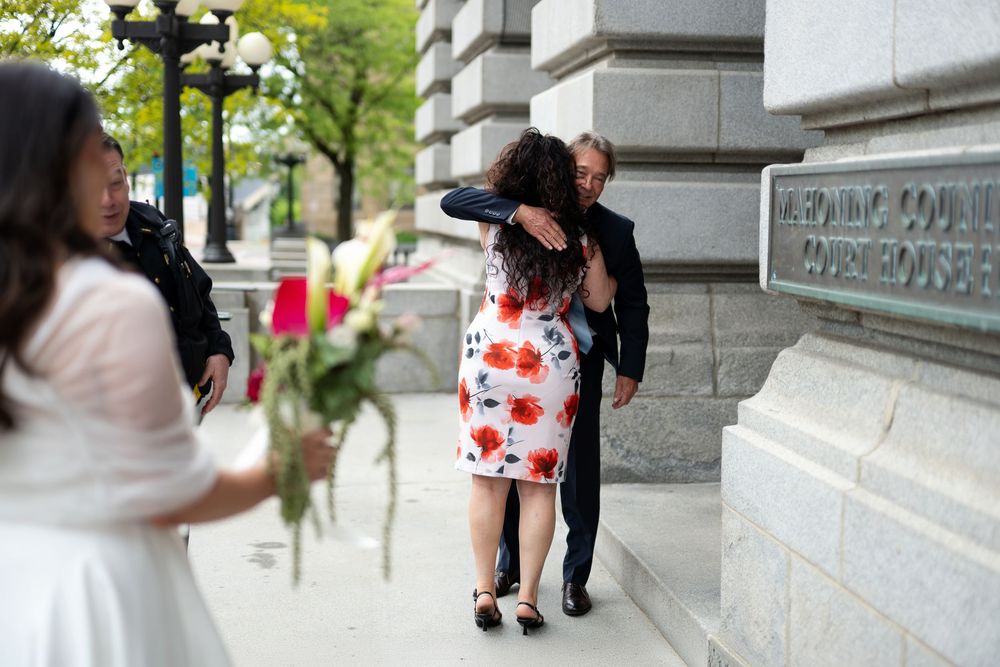 Groom hugging guest outside Hennepin County Courthouse after civil ceremony.