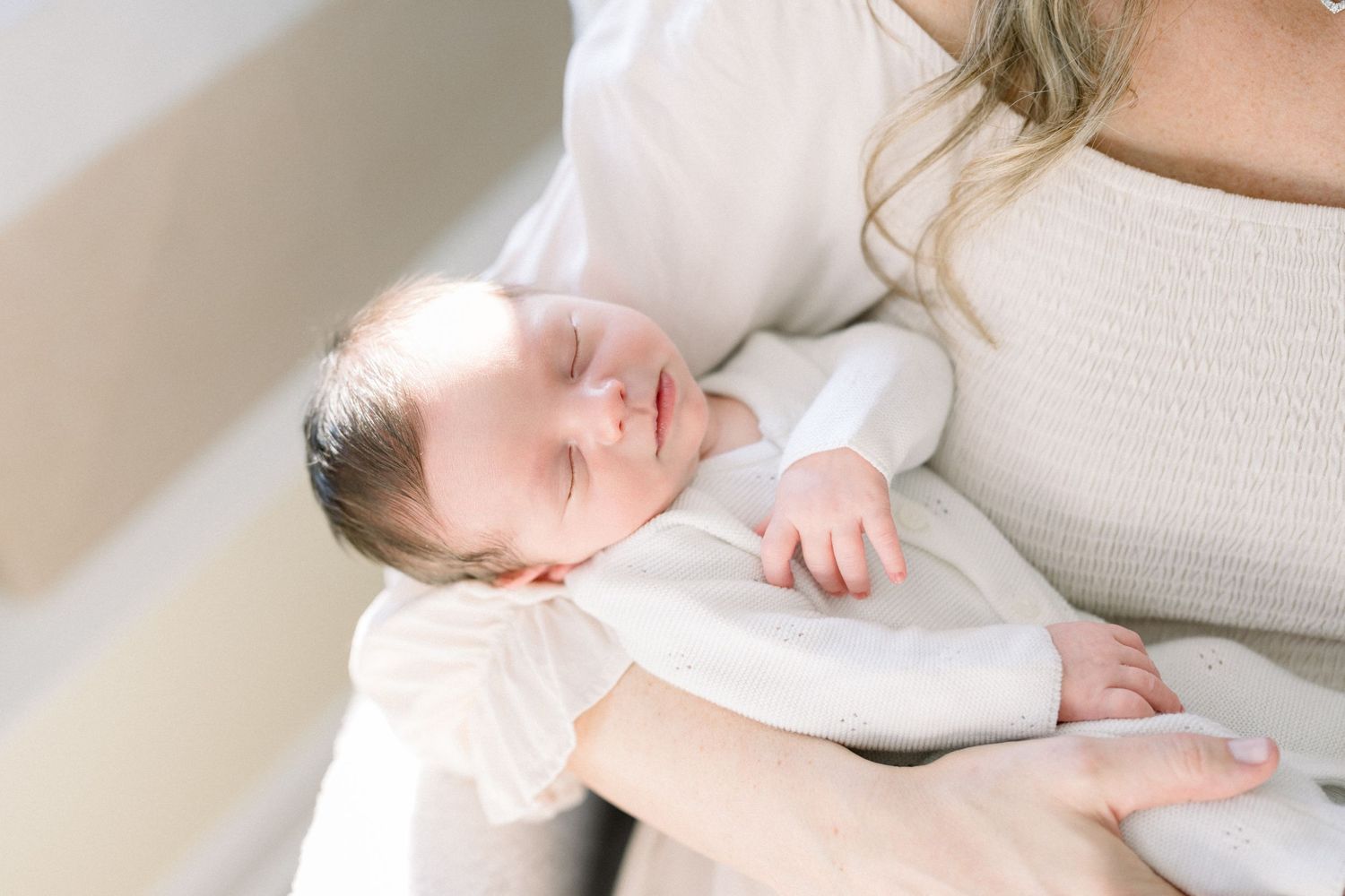 A peaceful newborn baby sleeping in mother's arms in a photoshoot in washington dc