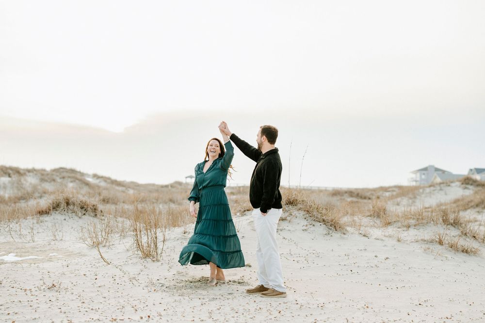 People in flowing outfits dance and move gracefully across white sand dunes in an artistic desert photoshoot.