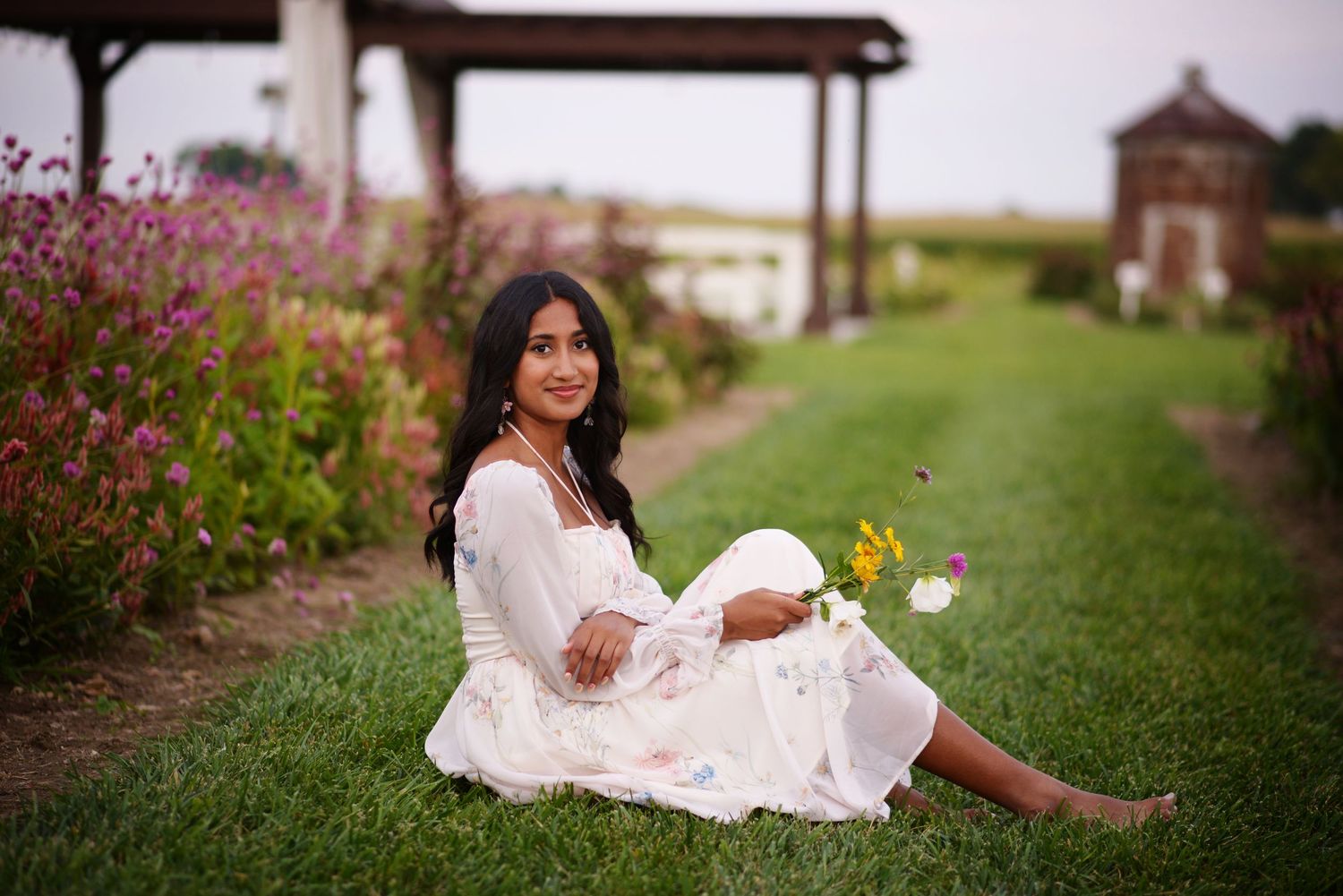 A young woman in a white dress poses gracefully on stone steps during an outdoor portrait session.