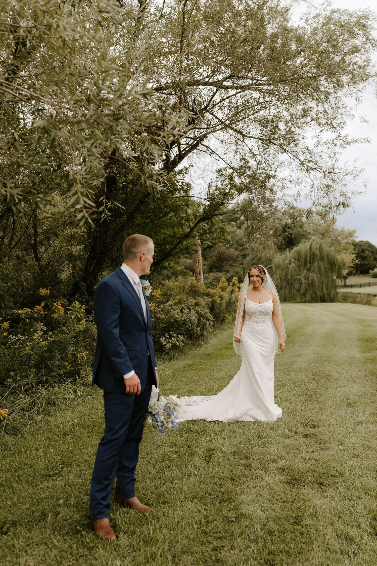 Bride holds a simple white tulip bouquet wrapped in white ribbon with a necklace attached.