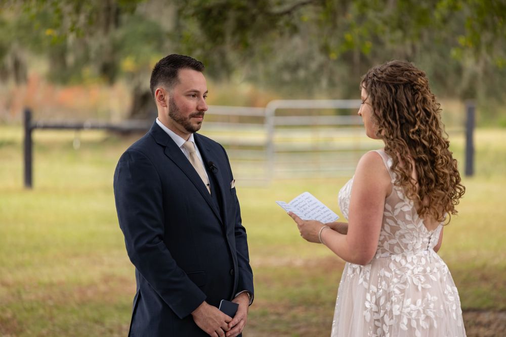 A couple shares an intimate moment during their wedding ceremony in a rustic outdoor setting.