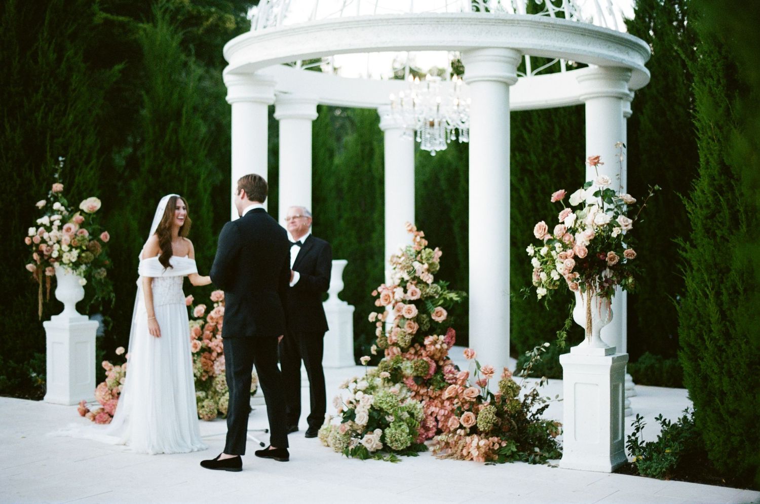 An elegant winter wedding reception features romantic white floral decor and candlelight in a grand venue setting.