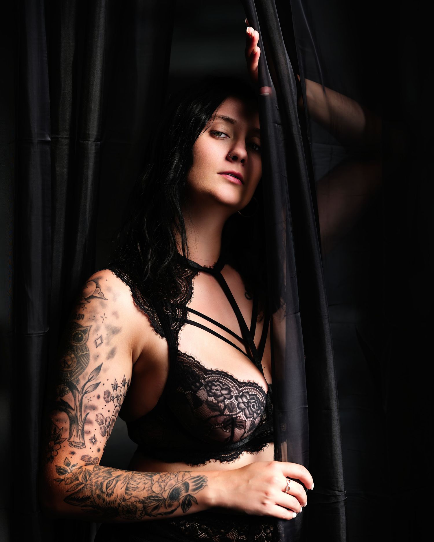 David G Holt Photography - Moody boudoir photography featuring tattooed model in black lace against dark backdrop.