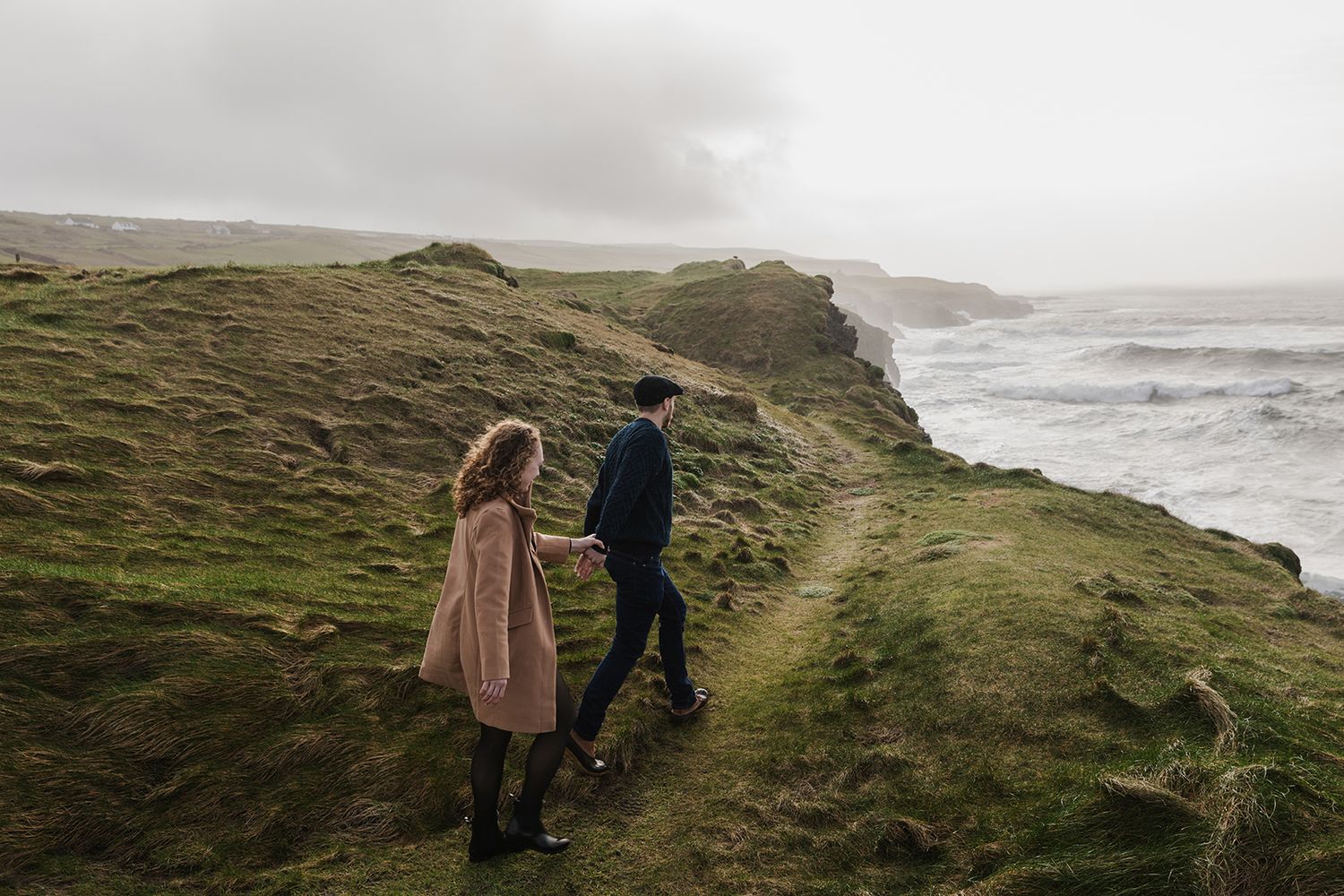 Storytelling sunset session at the Cliffs of Moher capturing couple walking along sea cliffs in Ireland