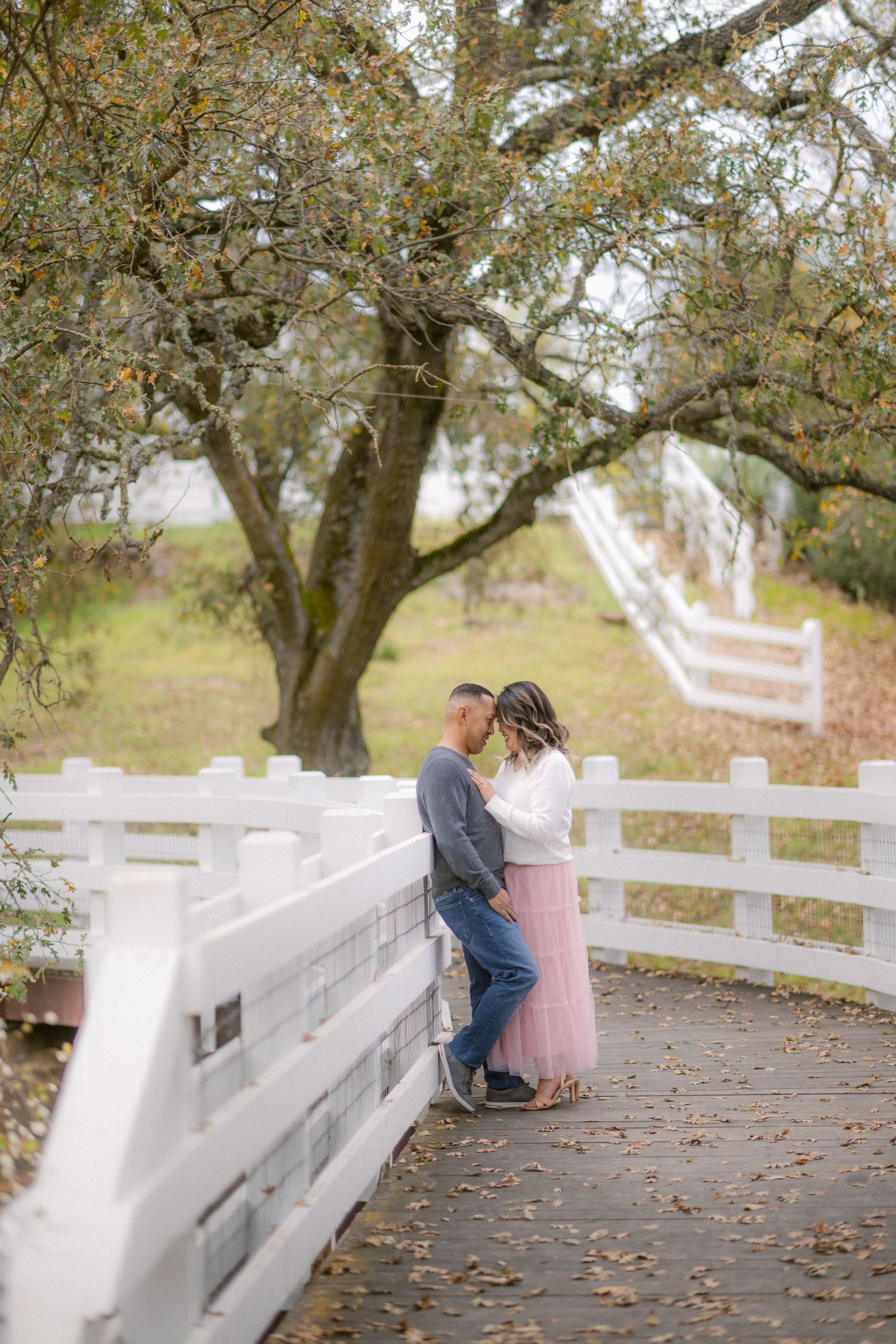 A romantic scene on a white bridge with autumn trees in the background.