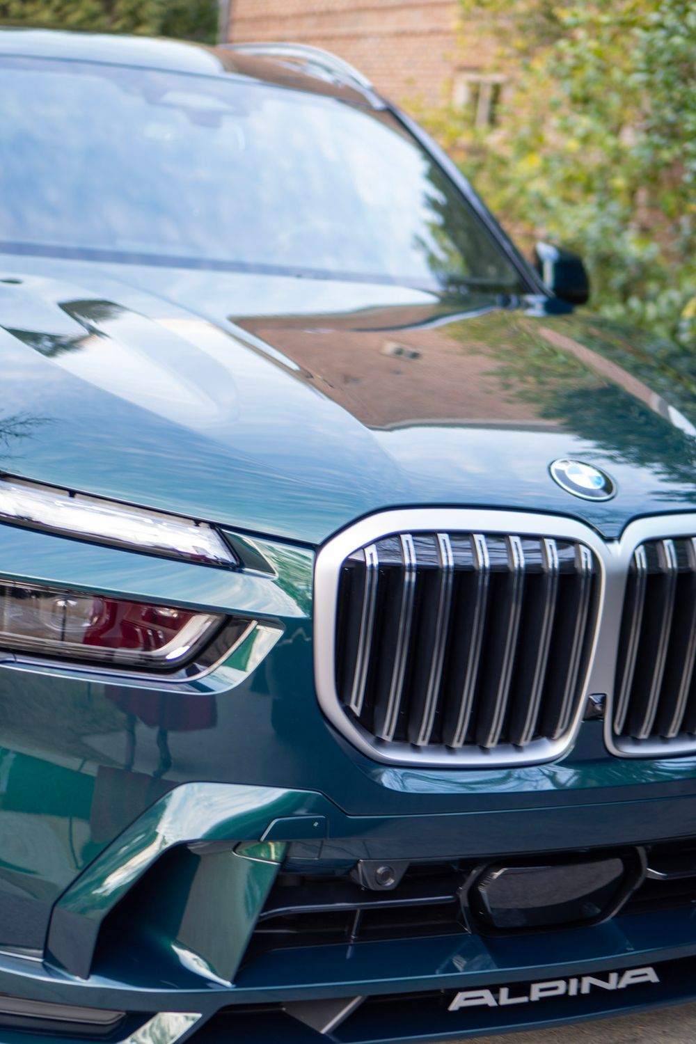 Close-up detail shots of a dark green BMW Alpina luxury car's front grille and hood sections.