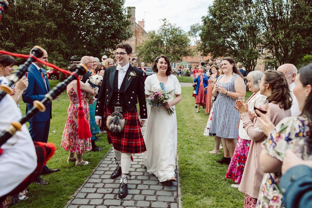 Wedding guests gather on a grassy lawn during an outdoor summer celebration.