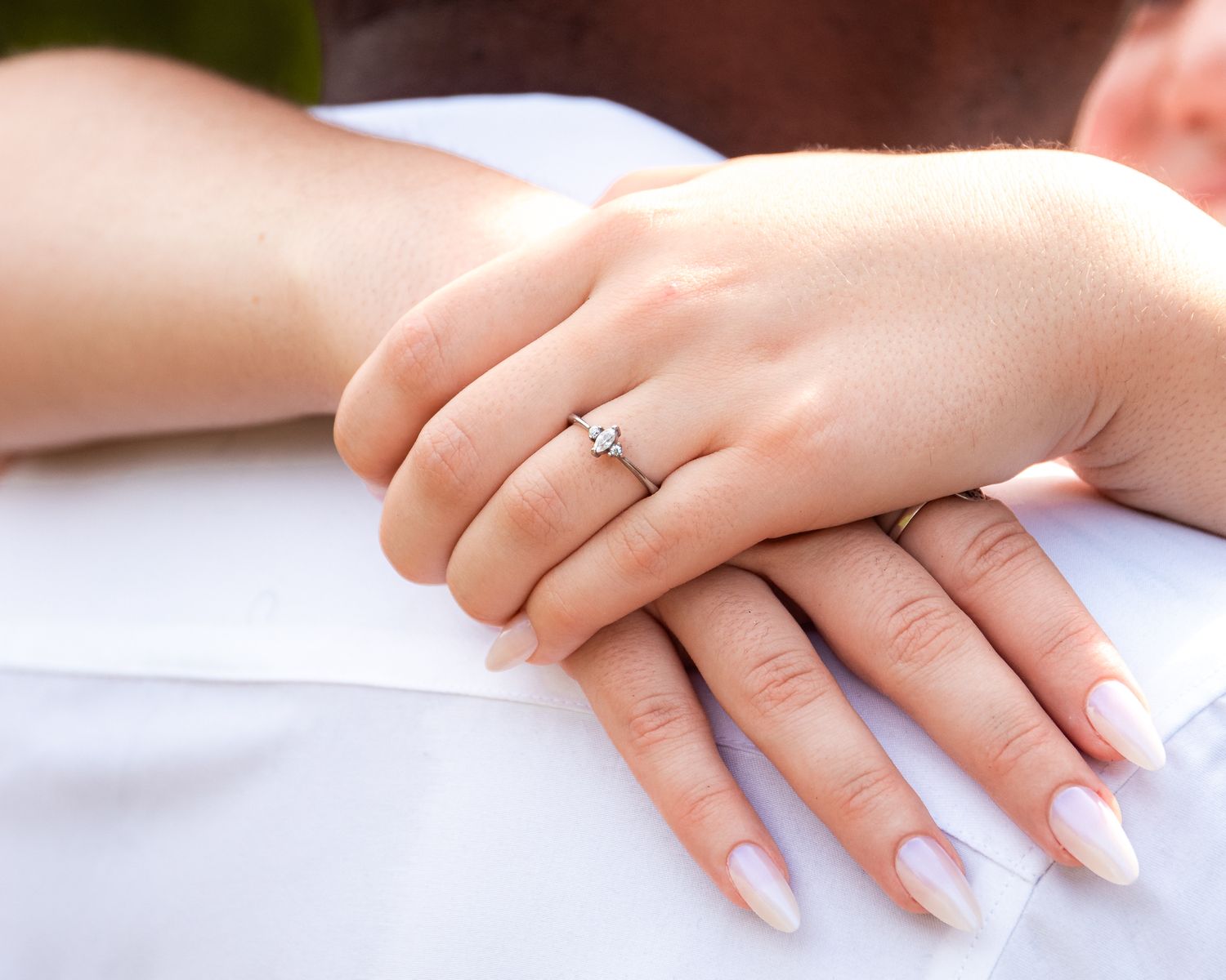 Close-up view of a hand with elegant white manicured nails against a soft neutral background.