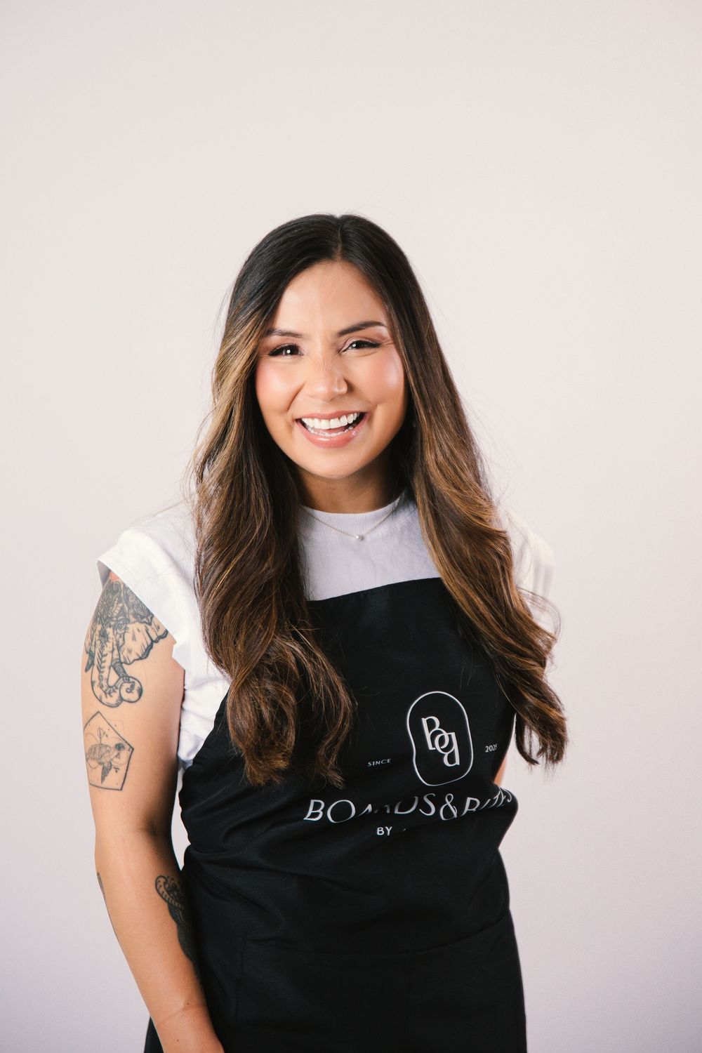 Lifestyle shots of black branded apron with Boards&Bites logo worn in studio setting.
