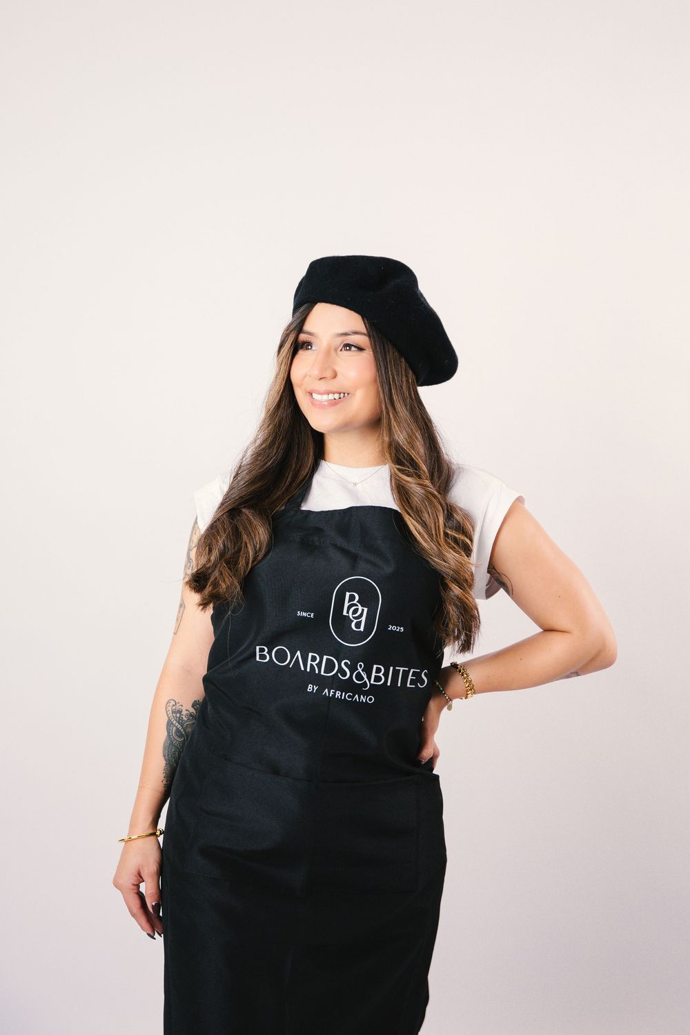 Professional studio photos showing black branded apron with Boards&Bites logo against white background.