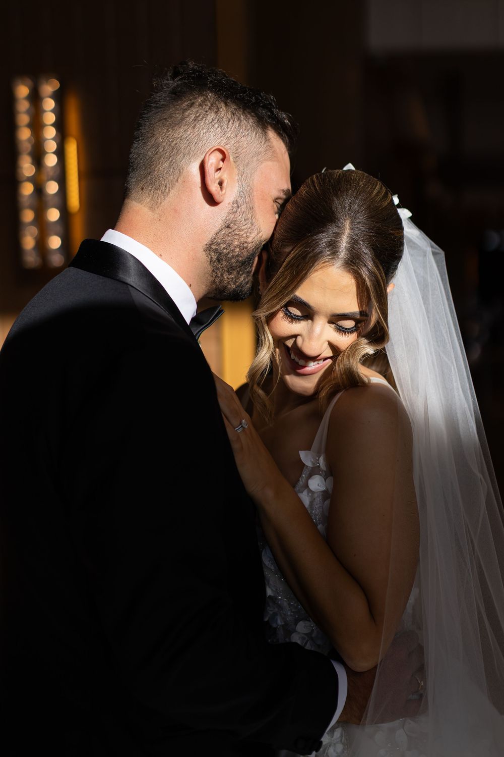 Romantic silhouetted sequence of newlyweds sharing intimate kisses in a dimly lit venue with glowing lights in background.