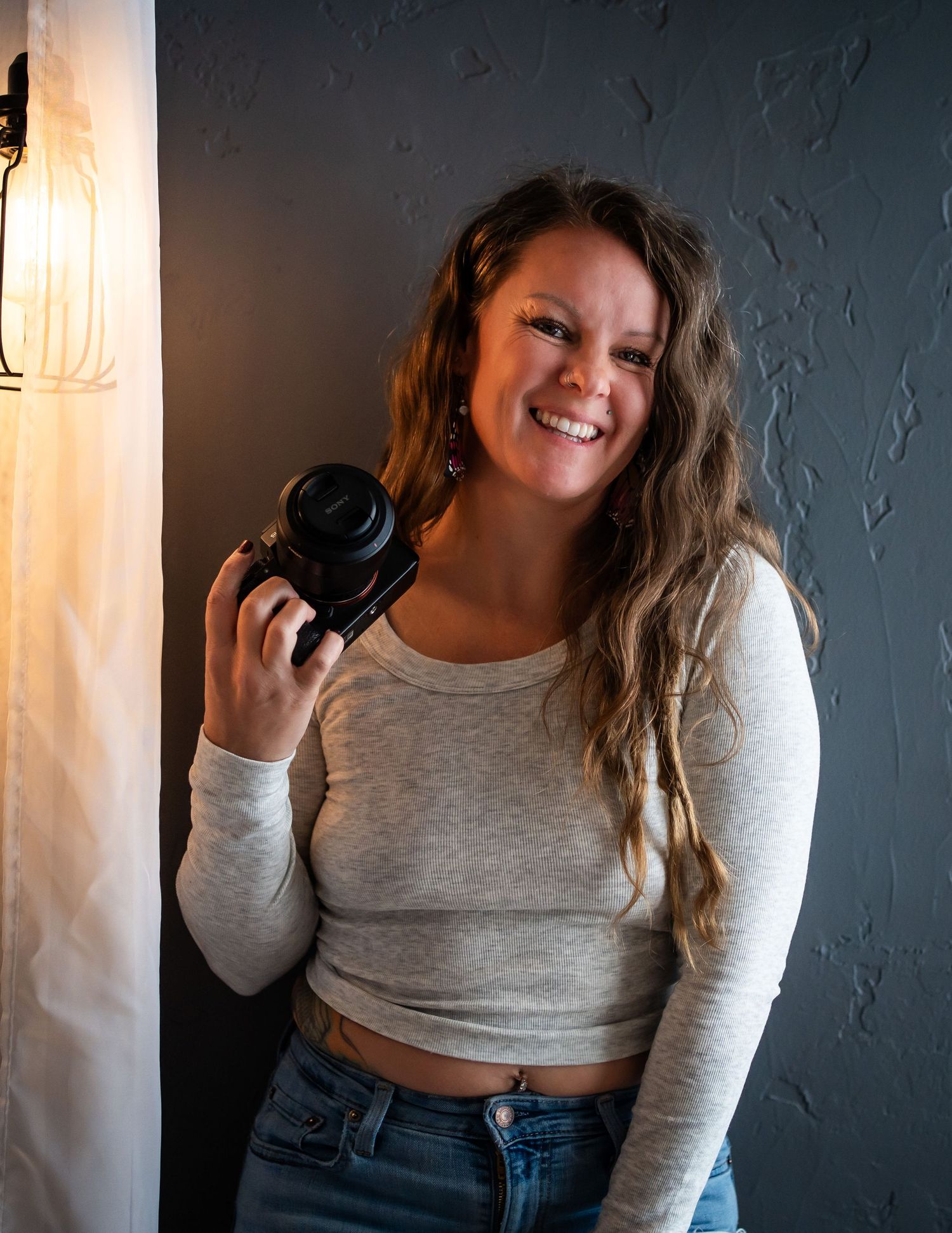 Person in gray long sleeve crop top and jeans poses playfully in multiple candid shots against a wall.