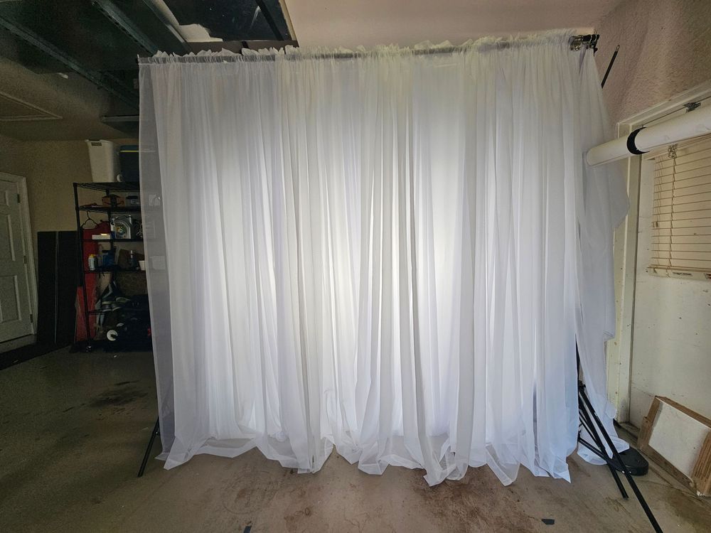 White sheer curtains hanging in a row along a wall create an elegant backdrop for an indoor space.