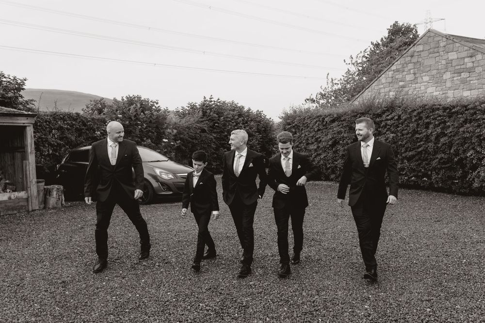 Black and white photo sequence of groomsmen walking in formation across a grassy field.