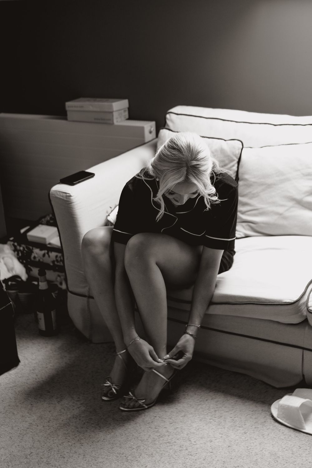 Black and white photo series showing someone putting on shoes while sitting on a white couch.