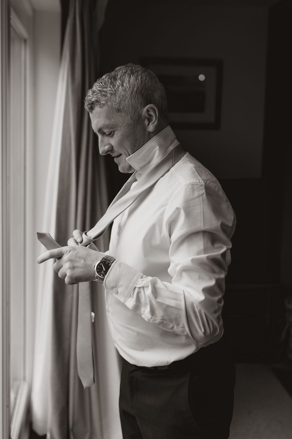 Series of black and white photos showing someone adjusting their formal attire near a window.