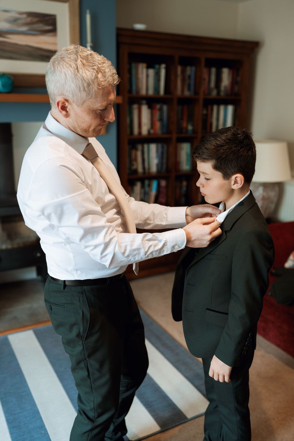 A touching moment of adjusting a young boy's formal attire before a special event.