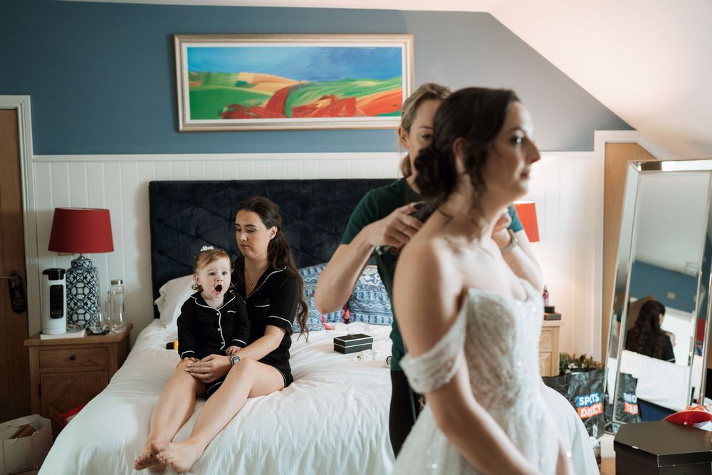 Getting ready scene with bridesmaids preparing in a blue-walled room before the ceremony.