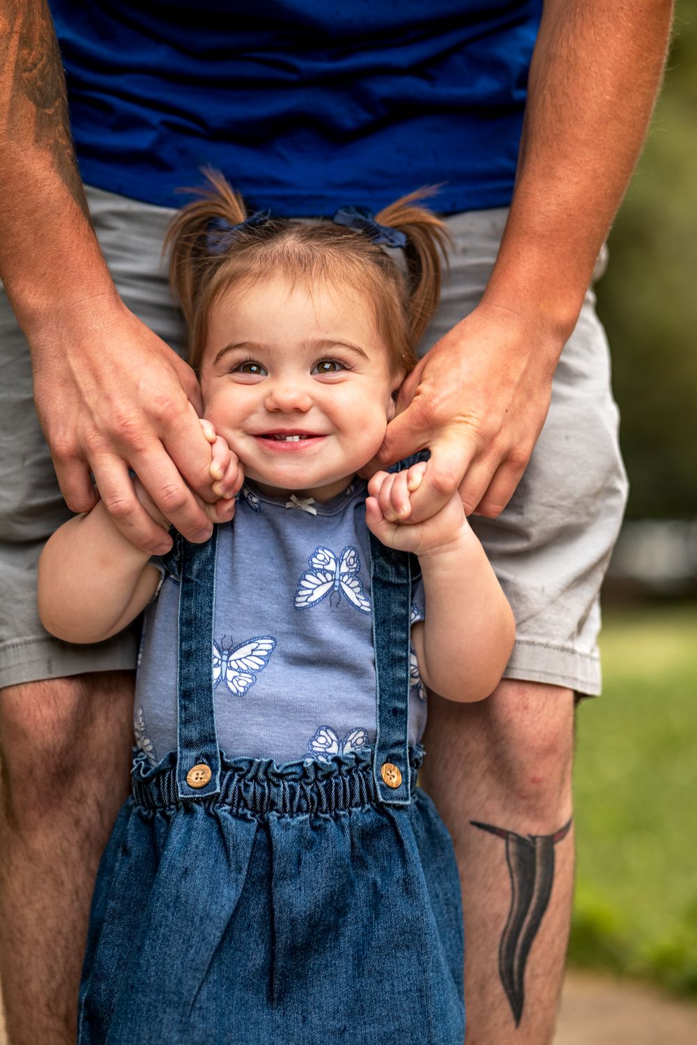 A series of four connected photos showing a small child in denim overalls being held by adult hands.