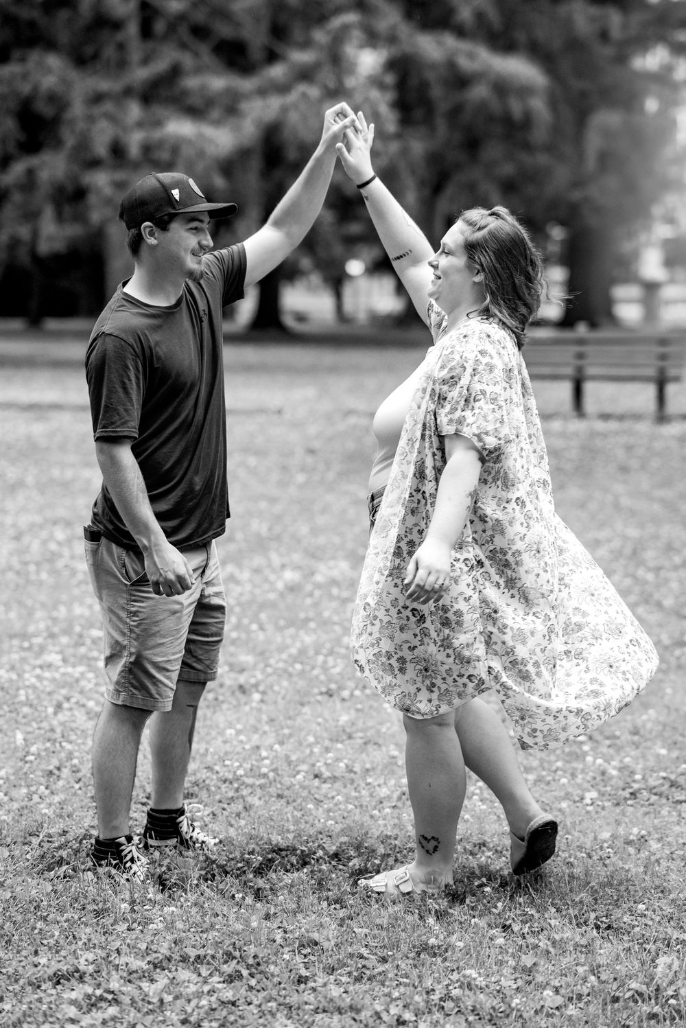 A couple dances playfully in a grassy field, creating a series of romantic black and white moments in motion.