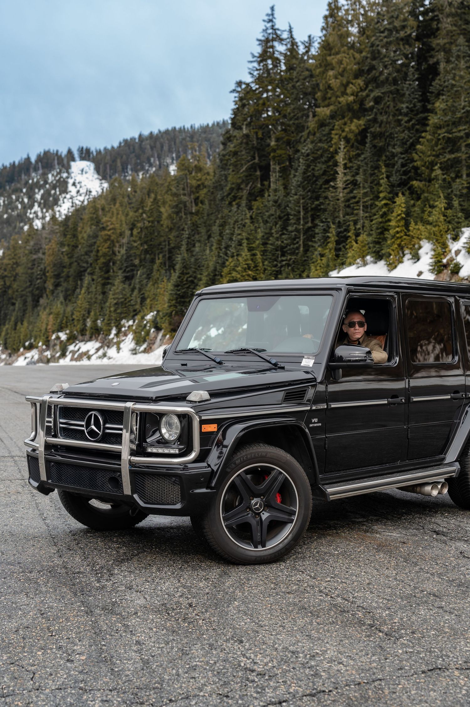 A black luxury SUV parked in a snowy mountain setting with doors open showing the interior.