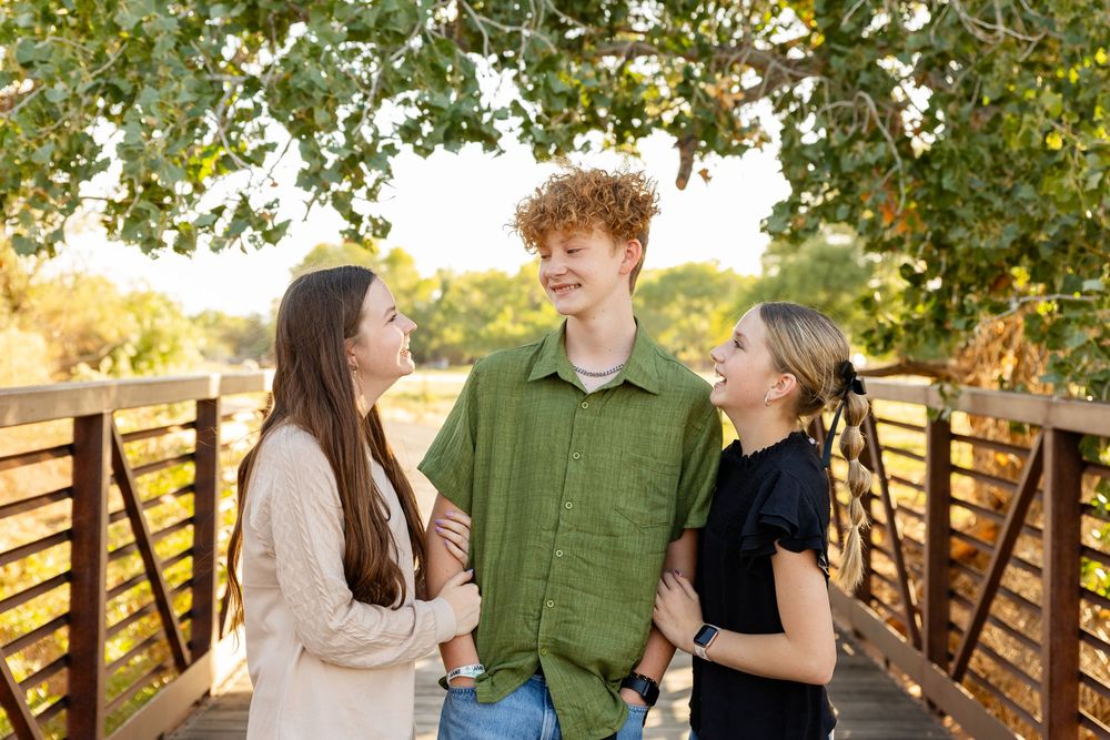 3 teenagers smile at each other in Southern utah at Kirkland farms bridge