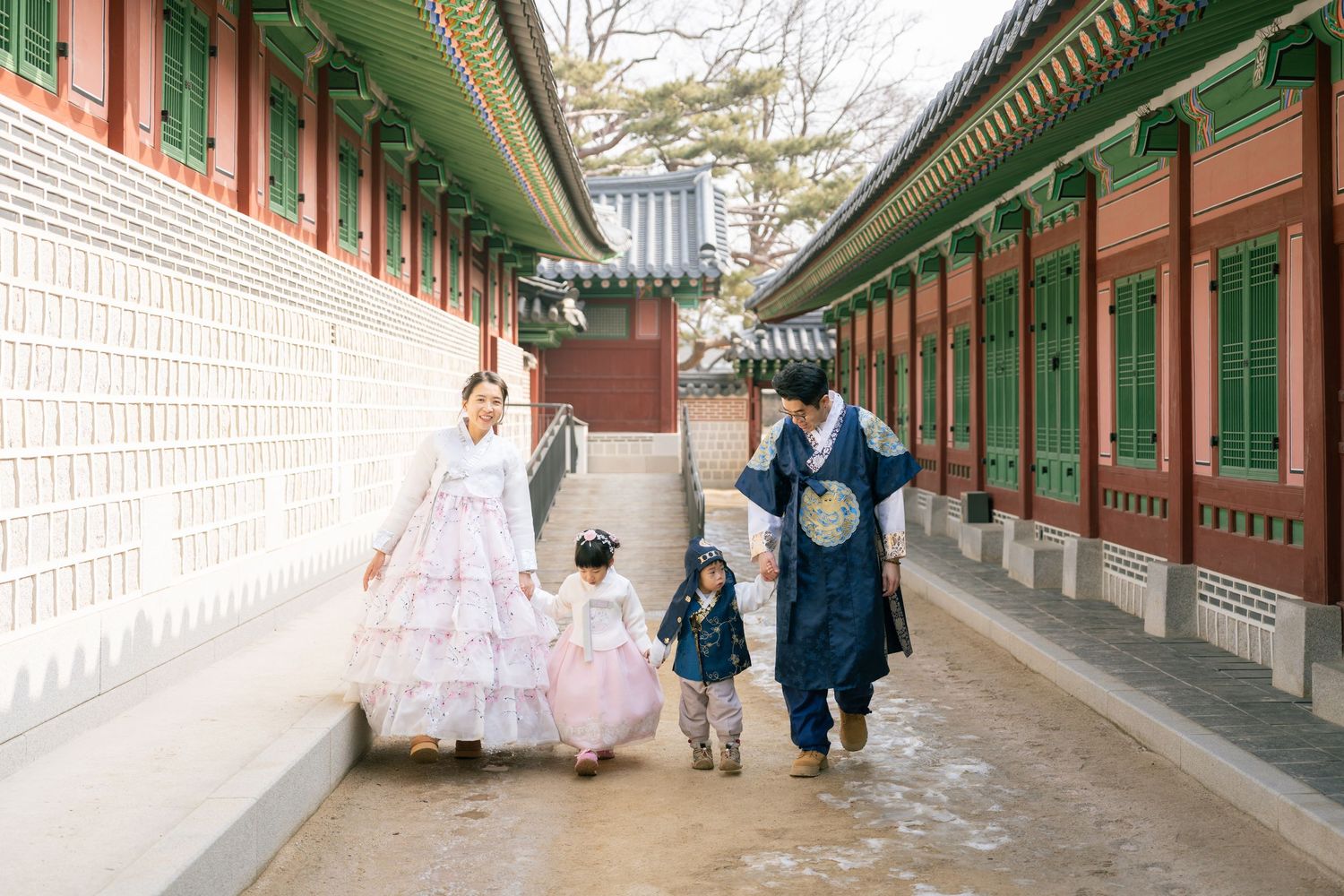People walking along a traditional Korean palace corridor with ornate wooden architecture and stone walls.