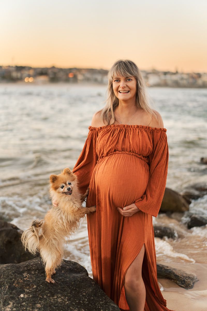 Maternity photoshoot at sunset with a small Pomeranian dog and burnt orange flowy dress for Mother's day photoshoot with a dog