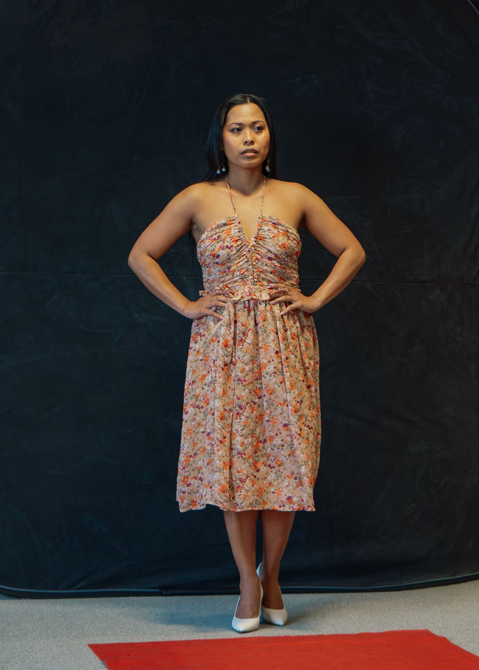 A model in a floral babydoll dress poses against a dark backdrop in a series of fashion photography shots.