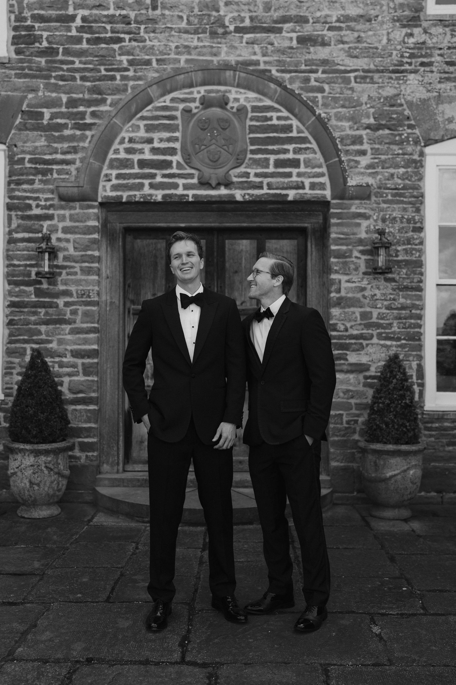groom and best man stood laughing with eachother outside dewsall court in herefordshire